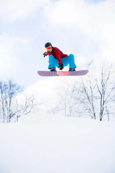 Photo d'athlète avec saut en snowboard dans une station enneigée — Photo