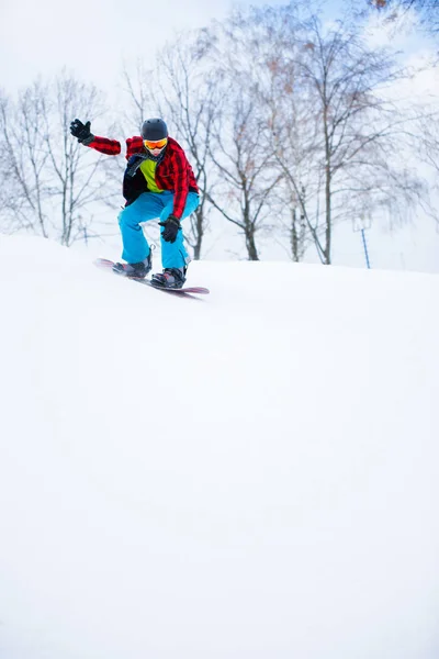 Imagem de desportista no capacete com snowboard equitação em resort nevado — Fotografia de Stock