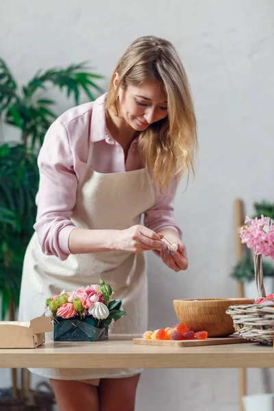 Portrait of young blonde florist composing bouquet of marshmallows, flowers — Stock Photo, Image
