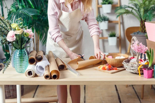 Florist girl cuts wrapping paper — Stock Photo, Image
