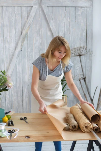 Jonge bloemist snijden van papier verpakking — Stockfoto