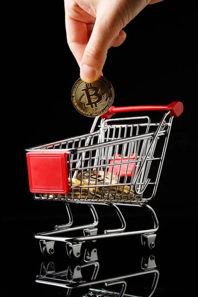 Hand wirft Bitcoin in Einkaufswagen. — Stockfoto