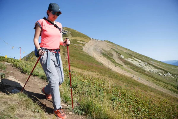 Foto de chica turística caminando con palos y mochila en la colina — Foto de Stock