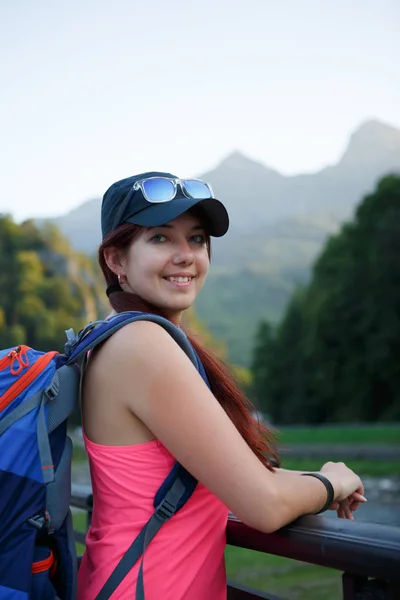 Foto de menina turística com mochila contra pano de fundo de montanhas pitorescas — Fotografia de Stock