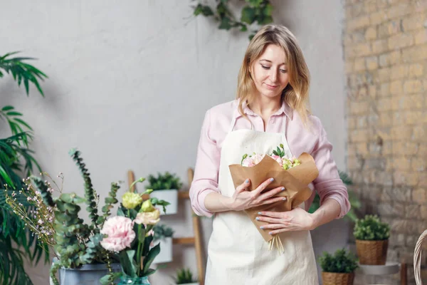 Photo of florist woman in apron with bouquet with kraft paper — Stock Photo, Image