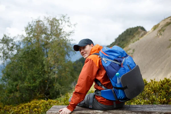 산의 배경에 배낭 발랄 한 웃는 남자의 사진 — 스톡 사진