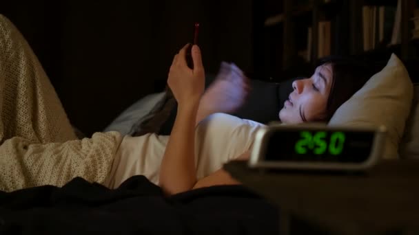 Γυναίκα που χρησιμοποιούν κινητό τηλέφωνο στο κρεβάτι τη νύχτα. — Αρχείο Βίντεο