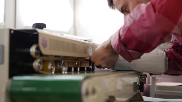 Человек упаковки кофе мешок из уплотнительной машины на заводе — стоковое видео