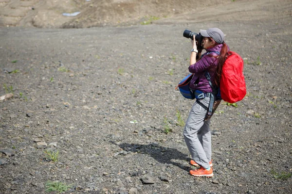 Foto einer Frau mit Rucksack und Kamera auf einem Hügel — Stockfoto