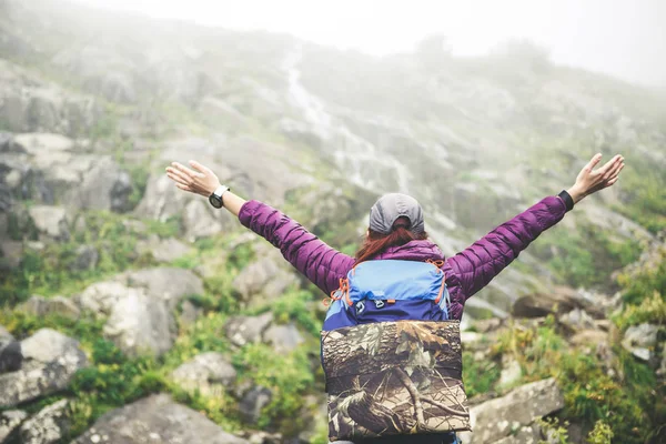 Foto von hinten von Mädchen mit Rucksack mit erhobenen Händen — Stockfoto