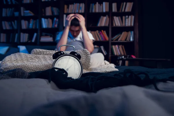 Photo of brunet with insomnia sitting in bed with alarm clock — Stock Photo, Image