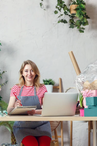 Photo of smiling florist woman with notepad at table — Stock Image Photo of smiling florist woman with notepad at table Royalty Free Stock Photos