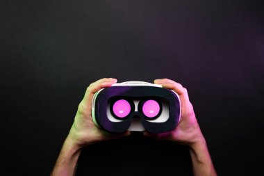 Siyah arka plan üzerine pembe ışık yanan ile sanal gerçeklik gözlük holding eller fotoğraf