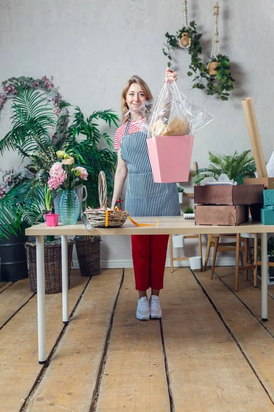Full-length photo of florist with floral composition at table with flowers, boxes — Stock Image Full-length photo of florist with floral composition at table with flowers, boxes Royalty Free Stock Photos