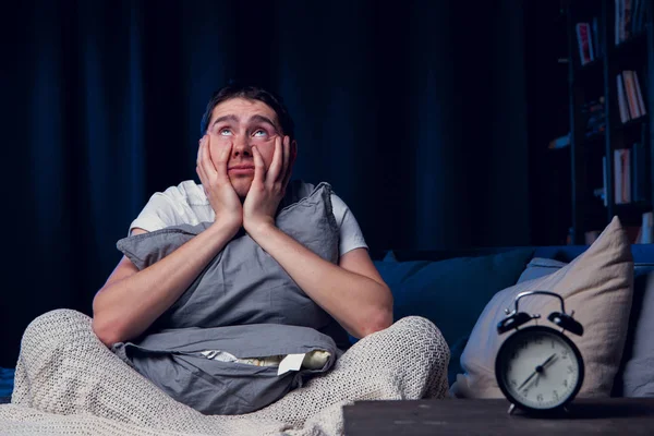 Imagen del hombre con insomnio con almohada sentada al lado de la alarma —  Fotos de Stock