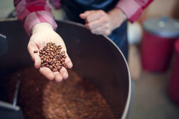 Imagen de mans hand con granos de café en tostadora industrial —  Fotos de Stock