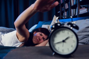 Çalar saat için kol germe Geceleri uykusuzluk ile memnun kadın resim