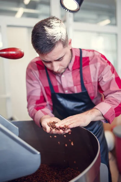 Foto de un joven empresario con granos de café en la mano al lado de la tostadora — Foto de Stock