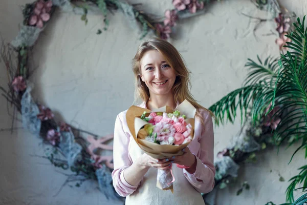 Foto de florista sonriente con ramo en las manos — Foto de Stock