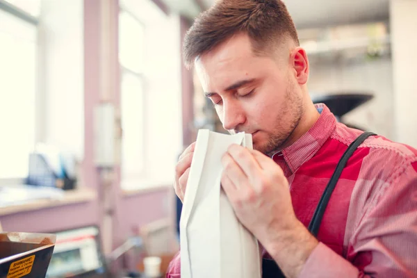 Foto de hombre olfateando café en bolsa de papel — Foto de Stock