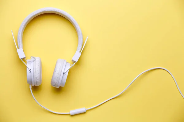 Photo of white headphones for music on yellow background