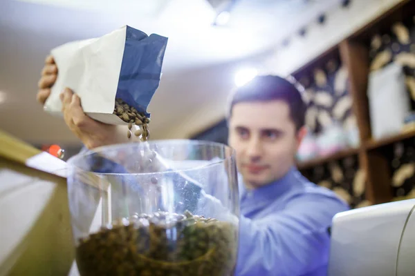 Foto de hombre barista vertiendo granos de café en un tazón de vidrio — Foto de Stock