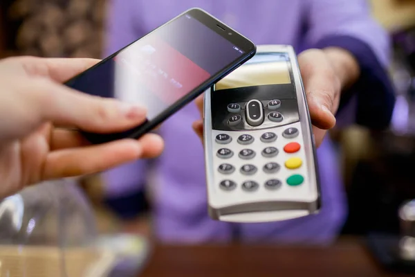 Φωτογραφία: αγοραστής πληρώνει με έξυπνο κινητό τηλέφωνο κοντά σε πωλητή με τερματικό — Φωτογραφία Αρχείου