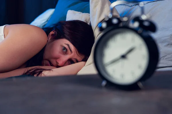 Brunette ágyon mellett ébresztőóra éjszaka álmatlanság képe — Stock Fotó