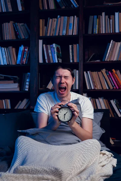 Foto av skrikande mannen med sömnlöshet sitter i sängen med väckarklocka — Stockfoto