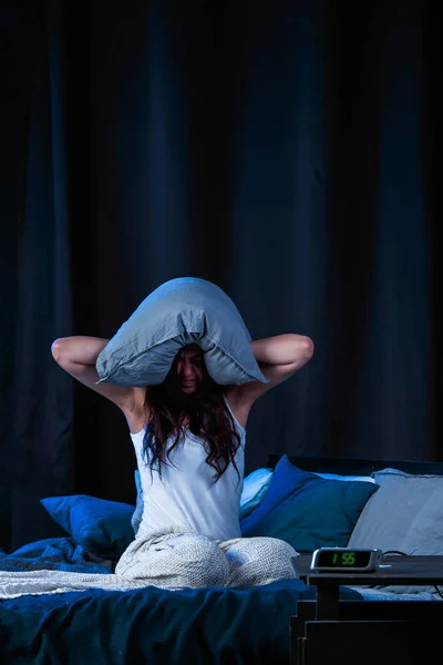 Foto av brunett med sömnlöshet med kudde på huvudet sitter på sängen — Stockfoto