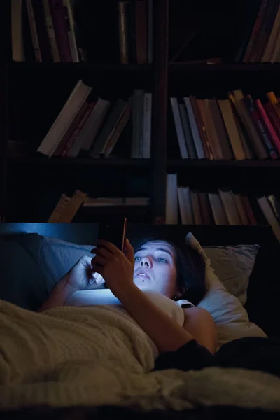 Фото женщины с телефоном, лежащей в постели ночью — стоковое фото