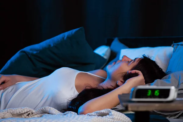 Kép fiatal nő álmatlanság ágyon következő óra — Stock Fotó