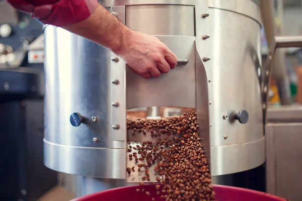 Photo de mans main ouvrant torréfacteur avec grains de café torréfiés — Photo