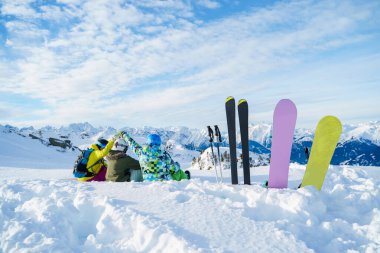 Photo from back of three athletes sitting in ski resort.
