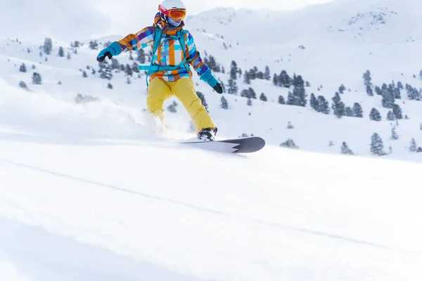 헬멧 과 마스크를 쓰고 있는 스포츠 여성 이 겨울날 눈덮인 산비탈에서 스노보드를 타고 있습니다. — 스톡 사진