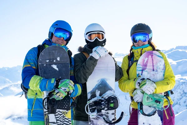 Foto de tres atletas con cascos y tablas de snowboard en las manos en el complejo de nieve . —  Fotos de Stock