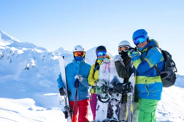 Foto de cuatro deportistas con casco y tabla de snowboard en el resort de nieve —  Fotos de Stock