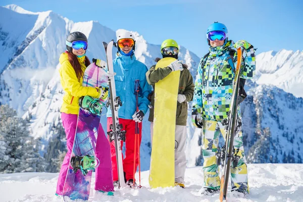 两名女运动员和两名男运动员带着雪橇和滑雪板站在滑雪胜地的照片 图库图片