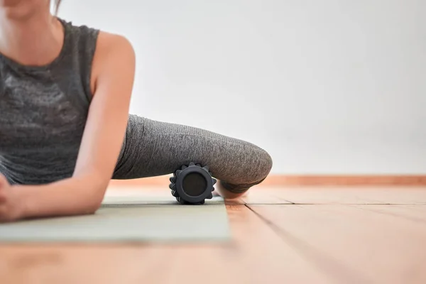 Donna che si allunga con massaggiatore seduta sul tappeto — Foto Stock