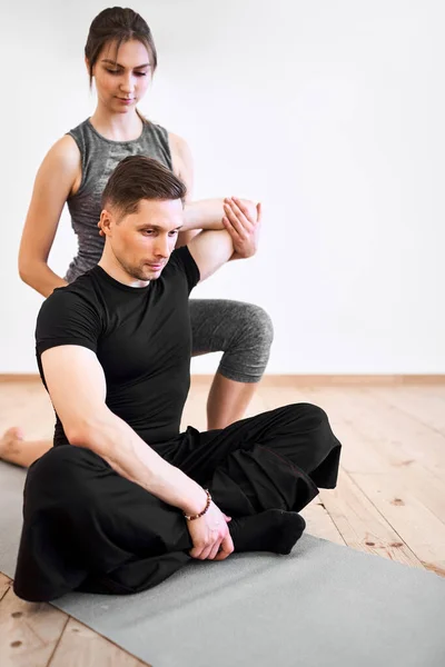 Młody mężczyzna i kobieta robi ćwiczenia rozciągające na siłowni — Zdjęcie stockowe