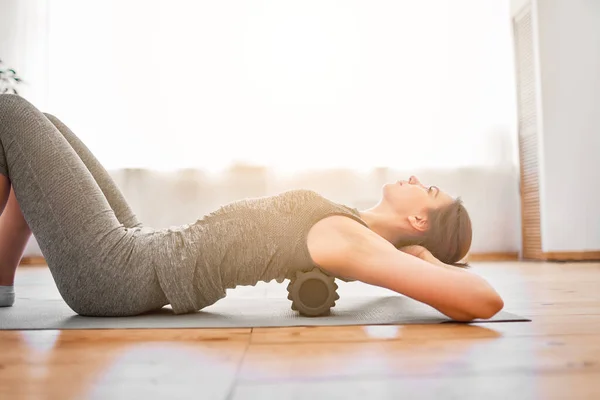 Donna che fa yoga sdraiato sul massaggiatore sul tappeto in palestra — Foto Stock