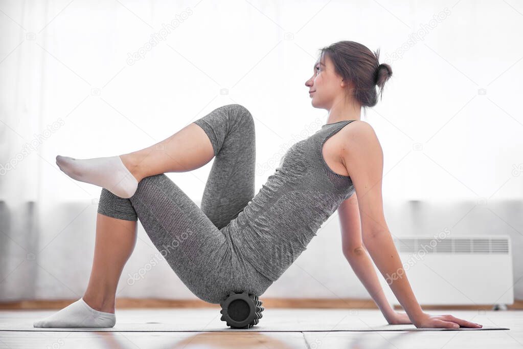 Young brunette in training with massager sitting on rug