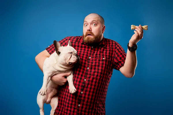 Meglepett férfi ing tartja bulldog és csont üres kék háttér — Stock Fotó