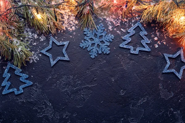 Image of branches of spruce, Christmas blue toys, burning garlands on black background — Stock Photo, Image
