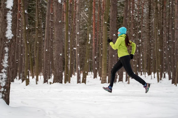Bild einer jungen Sportlerin beim Laufen im Winterwald — Stockfoto