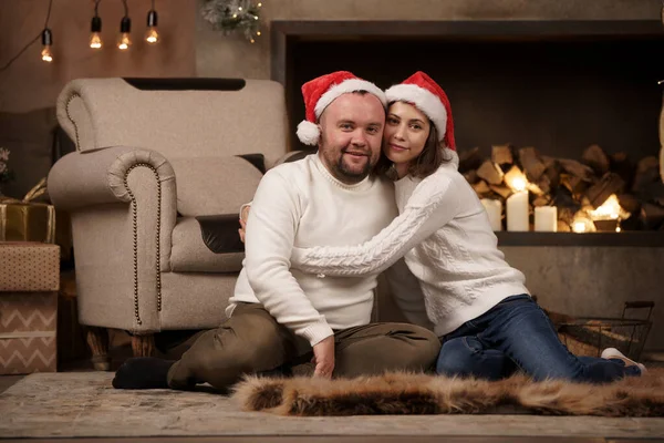 Εικόνα του άνδρα και της γυναίκας σε Santas καλύμματα κάθεται στο πάτωμα στο δωμάτιο — Φωτογραφία Αρχείου