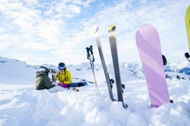 Kayak, kayak direkleri, arka planda kayak yapan termoslu iki kadın kışın kayak merkezinde oturuyor.