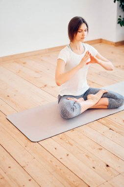 Genç esmer, gözleri kapalı halının üzerinde lotus pozisyonunda oturuyor.