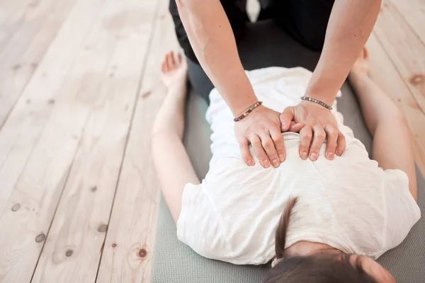 Hombre hace mujer espalda masaje en blanco camiseta acostado en gris alfombra — Foto de Stock