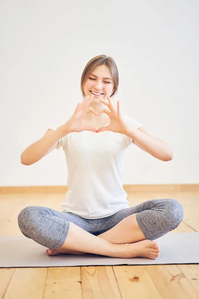 Smiling brunette woman sitting in lotus position on rug — Stock Photo, Image